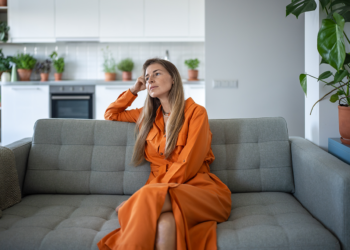 A thoughtful relaxed middle-aged woman resting on a sofa