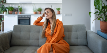 A thoughtful relaxed middle-aged woman resting on a sofa
