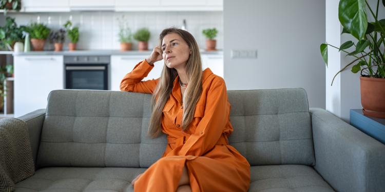 A thoughtful relaxed middle-aged woman resting on a sofa
