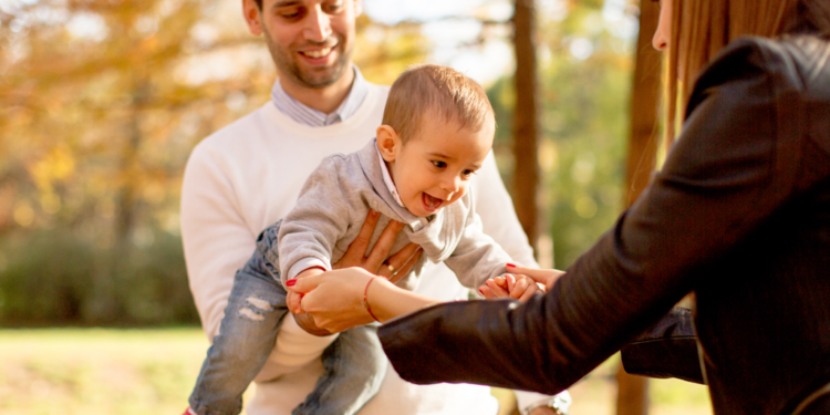 A couple plays with their baby in a park.