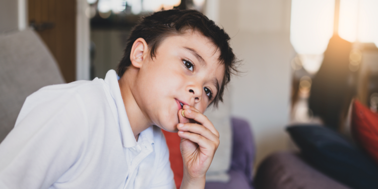 A kid looks sad as his fingers touch the lips.