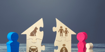 A wooden house with engraved icons of a car, a dog, and a couple, is torn into two pieces.