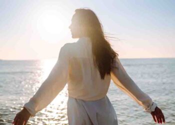 Young woman walking in the sunset on the beach.
