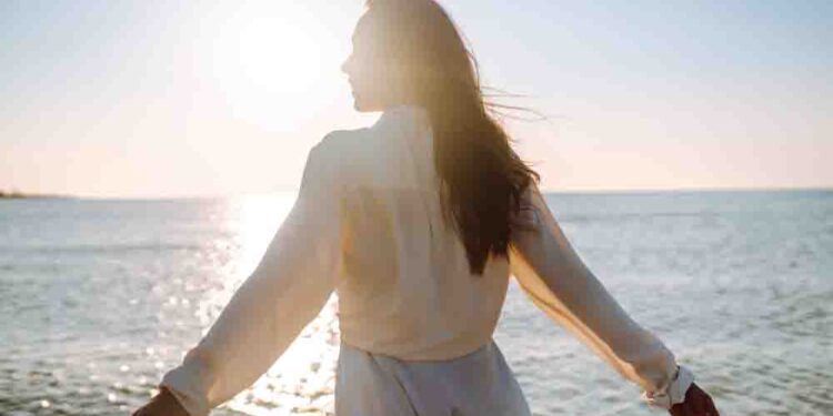 Young woman walking in the sunset on the beach.