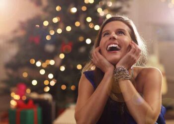 Happy woman sitting near Christmas tree