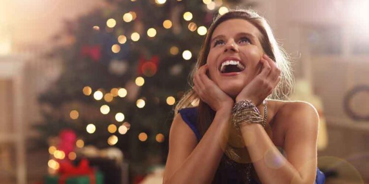 Happy woman sitting near Christmas tree