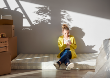 A woman loos pensive while sitting amid the boxes.