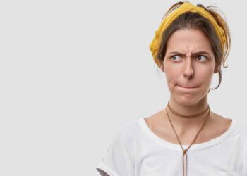 woman keeps lips pressed, has frustrated facial expression, frowns face in displeaure