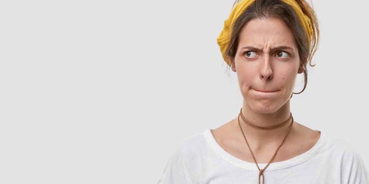 woman keeps lips pressed, has frustrated facial expression, frowns face in displeaure