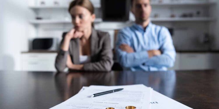 Focus of couple sitting at table with divorce documents