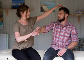 A woman touches the forehead of a man.