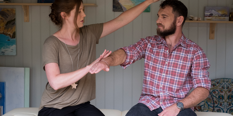 A woman touches the forehead of a man.