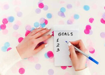 A woman writes goals on notepad.