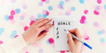 A woman writes goals on notepad.