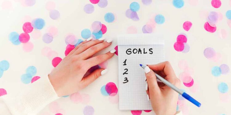 A woman writes goals on notepad.