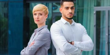 A confident successful couple looks angry while posing for a picture.