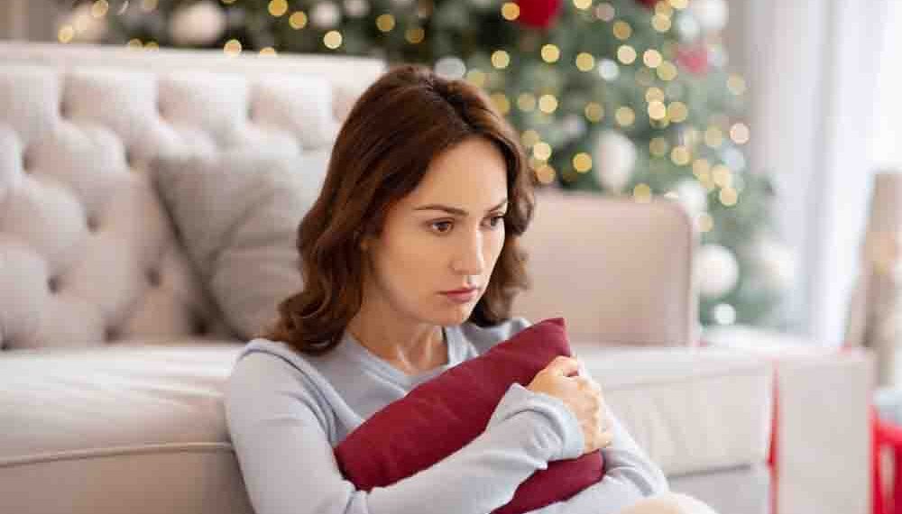 A single woman squeezes a cushion and looks pensive.