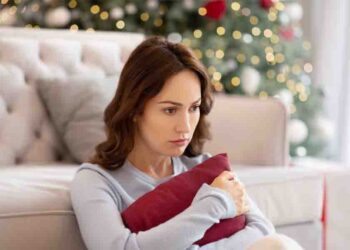 A single woman squeezes a cushion and looks pensive.