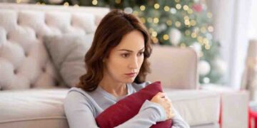 A single woman squeezes a cushion and looks pensive.